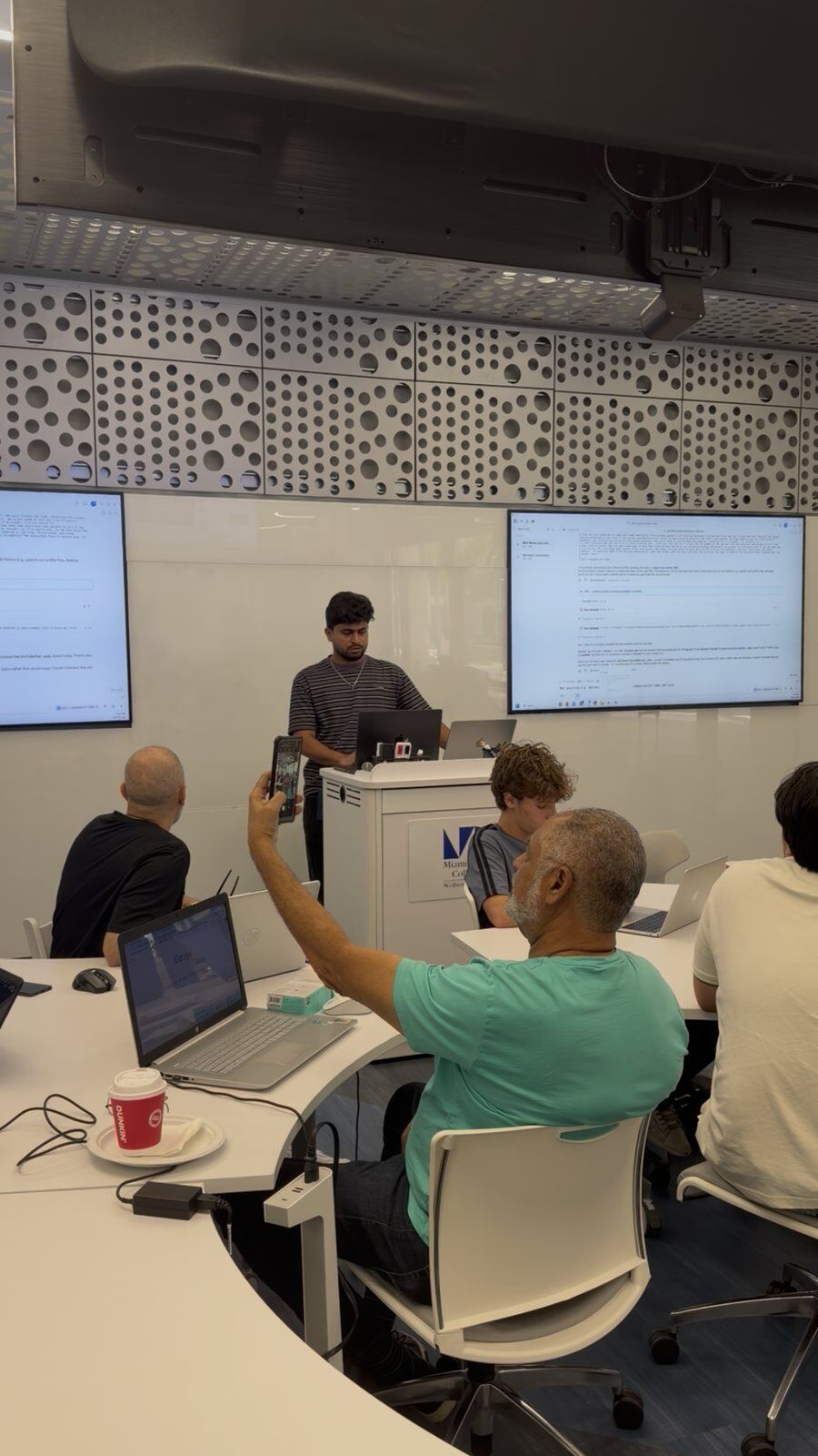 Demoing Iris at the Miami AI Hackathon. The console is on the screens behind, and the call runs live on speaker.